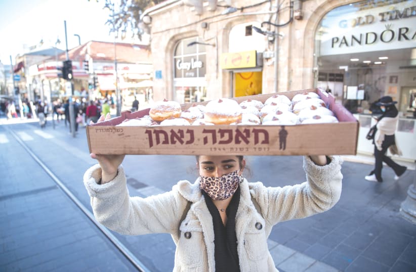 A YOUNG woman carries a tray of sufganiyot in the center of Jerusalem. Here in Israel, we celebrated Hanukkah openly, unashamedly and without fear. (photo credit: YONATAN SINDEL/FLASH90)