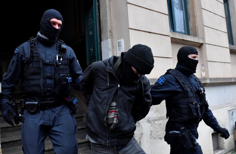 Police detain a suspect during raids in several locations in Dresden, Germany, December 15, 2021. (photo credit: REUTERS/MATTHIAS RIETSCHEL)