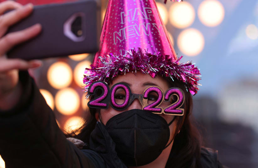  Teresa Hui, 40, of Brooklyn, wears 2022 numeral glasses and a face mask in Times Square ahead of New Year's Eve celebrations, in Manhattan, New York City (photo credit: REUTERS/ANDREW KELLY)