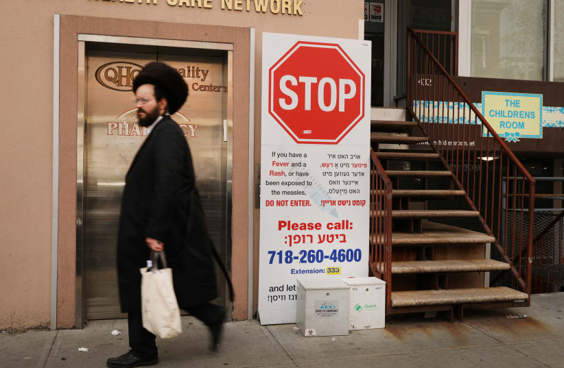  A sign warns people of measles symptoms in the Orthodox Jewish community in Williamsburg, Brooklyn in 2019.  (photo credit: SPENCER PLATT/GETTY IMAGES/JTA)