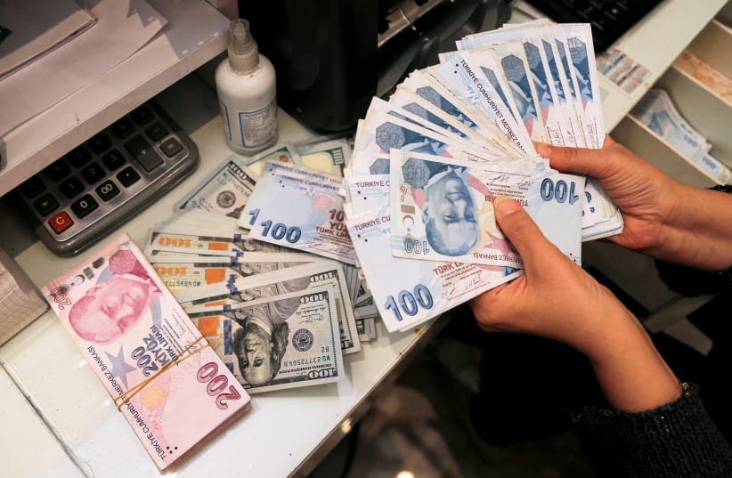 A money changer holds Turkish lira banknotes at a currency exchange office in Ankara, Turkey October 12, 2021.  (photo credit: REUTERS/CAGLA GURDOGAN)