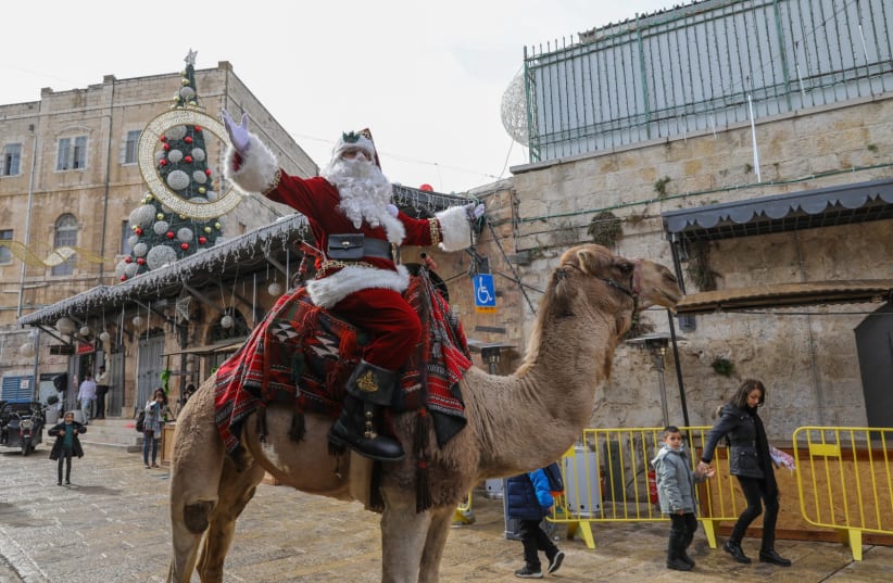  Issa Kassissieh, dressed as Santa Claus, rides a camel in Jerusalem's Old City, on December 23, 2021. (photo credit: MARC ISRAEL SELLEM/THE JERUSALEM POST)