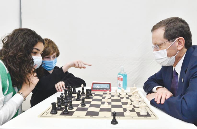  PRESIDENT ISAAC HERZOG pitted against junior chess players Sahar Mansour and Adam Pels.  (photo credit: HAIM ZACH/GPO)