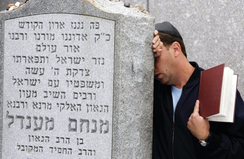  A MAN PRAYS at the graveside of the Lubavitcher Rebbe, Rabbi Menachem Mendel Schneerson, at the Old Montefiore Cemetery in New York. (photo credit: REUTERS/SHANNON STAPLETON)