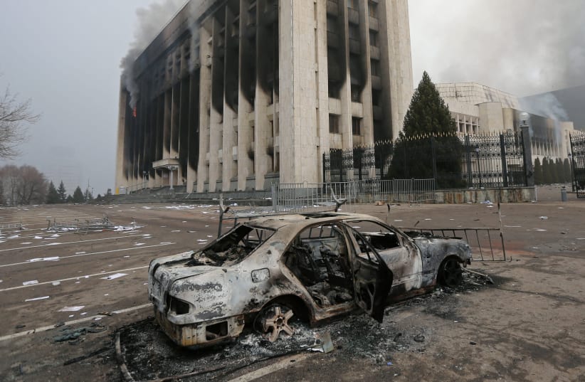 A burned car is seen in front of the mayor's office building which was torched during protests triggered by fuel price increase in Almaty, Kazakhstan, January 6, 2022. (photo credit: REUTERS/PAVEL MIKHEYEV)