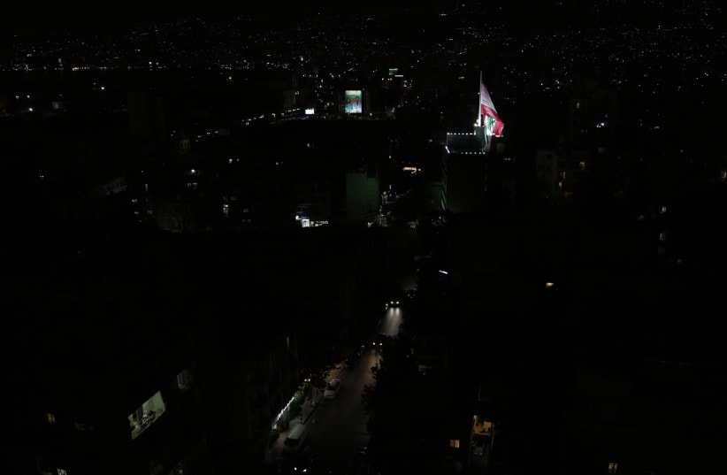  A Lebanese flag flutters near unlit residential buildings during a partial blackout in Beirut, Lebanon August 11, 2021 (photo credit: REUTERS/ISSAM ABDALLAH)