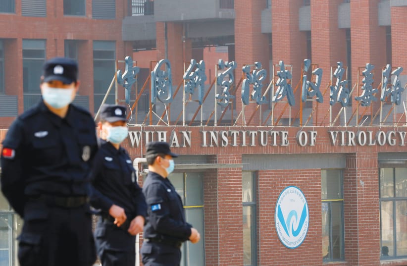  CHINESE SECURITY PERSONNEL keep watch outside the Wuhan Institute of Virology during a visit last year by a  World Health Organization team tasked with investigating the origins of COVID-19. (photo credit: THOMAS PETER/REUTERS)