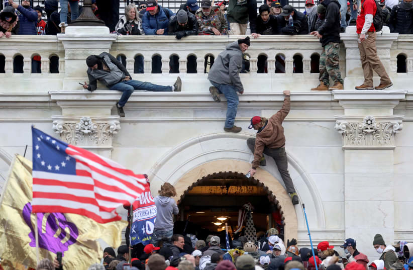  A mob of supporters of U.S. President Donald Trump fight with members of law enforcement at a door they broke open as they storm the US Capitol Building in Washington, US, January 6, 2021.  (photo credit: LEAH MILLIS/REUTERS)