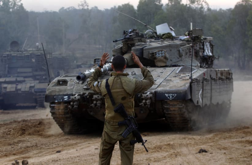  An Israeli soldier guides a tank at an Israeli Defnce Forces (IDF) staging area by the central Gaza border November 22, 2012.  (photo credit: YANNIS BEHRAKIS/REUTERS)