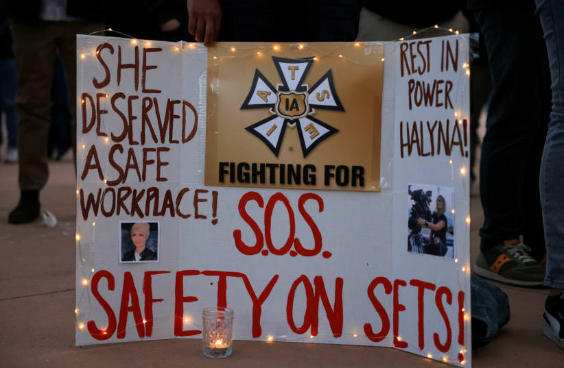  A woman displays a sign calling for workplace safety at a vigil for cinematographer Halyna Hutchins, who died after being shot by Alec Baldwin on the set of his movie "Rust", in Albuquerque, New Mexico, US, October 23, 2021. (photo credit: REUTERS/KEVIN MOHATT)