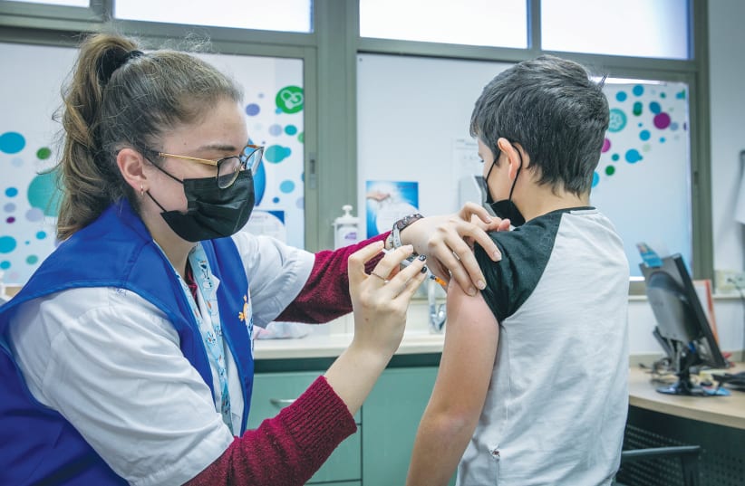 A child receives the COVID-19 vaccine at a temporary Maccabi healthcare center in Rehovot on Monday. (photo credit: YOSSI ALONI/FLASH90)
