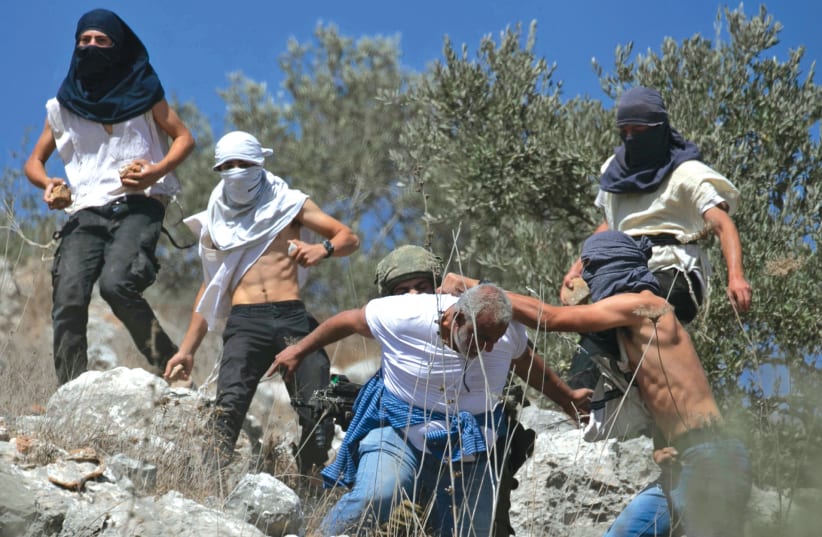  MASKED ISRAELIS clash with a Palestinian olive farmer from the village of Hawara near the settlement of Yitzhar in October 2020. (photo credit: JAAFAR ASHTIYEH/AFP via Getty Images)