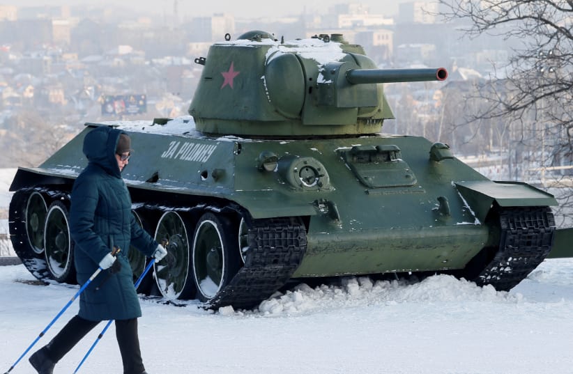  A woman passes by a T-34 tank and other Soviet-era military vehicles while practising nordic walking in a park in the rebel-held city of Donetsk, Ukraine January 27, 2022. (photo credit: REUTERS/ALEXANDER ERMOCHENKO)