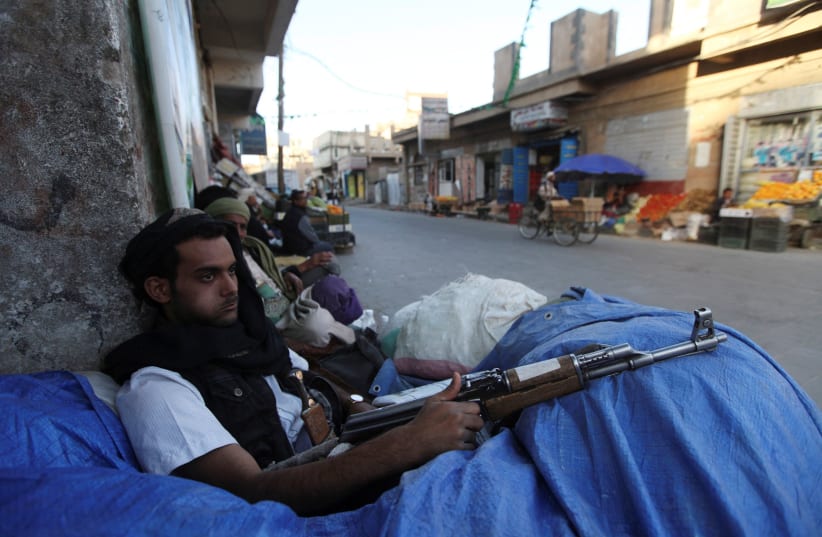   A Shi'ite Houthi fighter sits behind sandbags near a checkpoint in Sanaa December 17, 2014 (photo credit: REUTERS/MOHAMED AL-SAYAGHI)