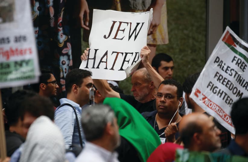  A pro-Israel demonstrator carries a sign accusing pro-Palestinian protesters of hating Jews, during a confrontation in Times Square in New York City (photo credit: CARLO ALLEGRI/REUTERS)