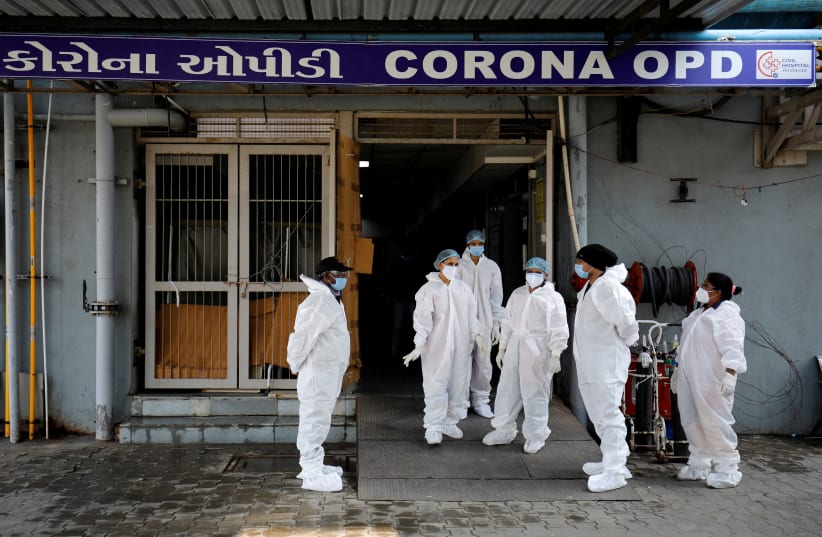  Healthcare workers wearing personal protective equipment (PPE) stand at the entrance of a coronavirus disease (COVID-19) hospital in Ahmedabad, India, January 7, 2022. (photo credit: REUTERS/AMIT DAVE)