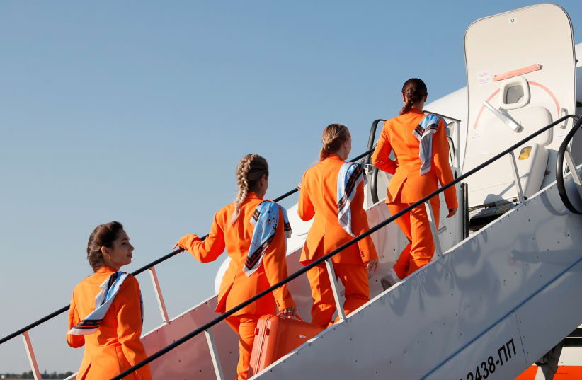 Flight attendants of SkyUp Airlines walk up the stairs while boarding a plane as they take part in the presentation of a new uniform at the Boryspil International Airport outside Kyiv, Ukraine September 30, 2021. (photo credit: GLEB GARANICH/REUTERS)