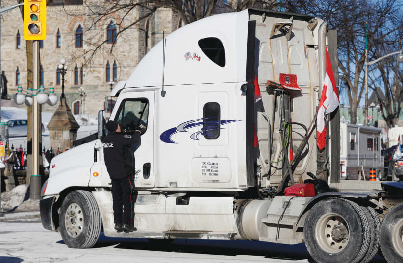  AN OTTAWA POLICE officer speaks with a truck driver, as truckers and supporters continued to protest coronavirus vaccine mandates, in Ottawa on Monday. (photo credit: Lars Hagberg/Reuters)