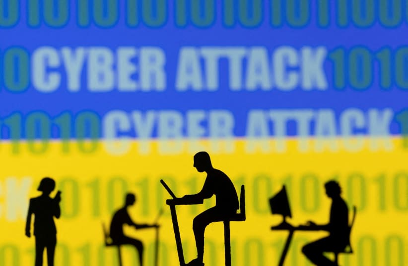   Figurines with computers and smartphones are seen in front of the words "Cyber Attack", binary codes and the Ukrainian flag, in this illustration taken February 15, 2022. (photo credit: DADO RUVIC/REUTERS)