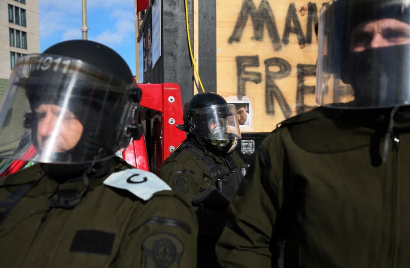  Police officers stands guard, while truckers and supporters continue to protest coronavirus disease (COVID-19) vaccine mandates, on Wellington Street in Ottawa, Ontario, Canada, February 18, 2022.  (photo credit: SHANNON STAPLETON/ REUTERS)