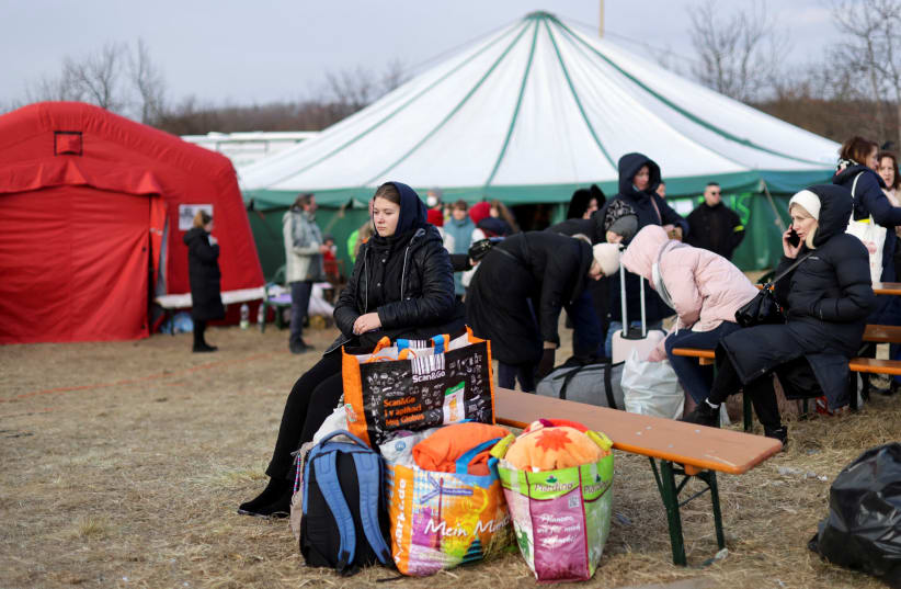  A woman sits on a bench next to luggage as refugees from Ukraine cross the Ukrainian-Slovakian border following Russia's invasion of Ukraine, in Vysne Nemecke, Slovakia, March 3, 2022.  (photo credit: REUTERS/LUKASZ GLOWALA)