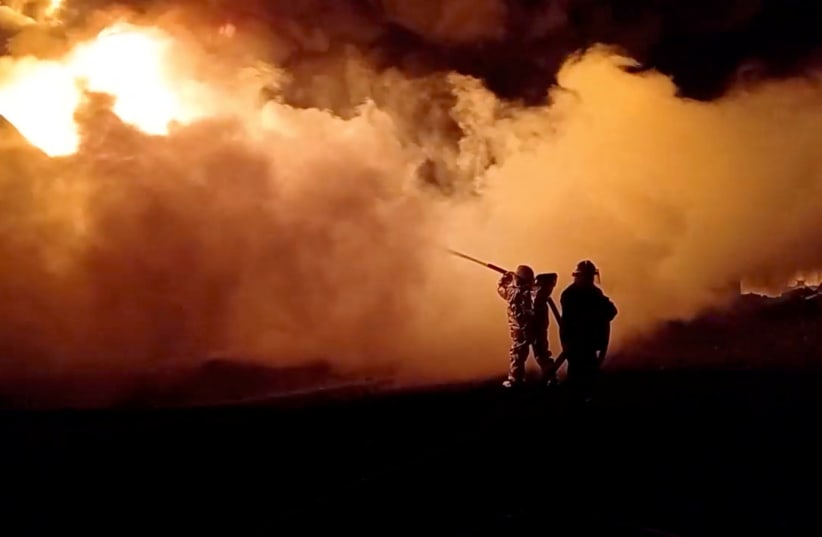  Fire fighters extinguish fire in an oil depot that Ukraine's State Emergency Services say was caused by Russian strikes in Zhytomyr region, Ukraine March 7, 2022 in this still image obtained from a handout video. (photo credit: State Emergency Services of Ukraine/Handout via REUTERS)
