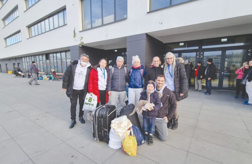  MEMBERS OF the delegation pose with a family they helped to make aliyah. They are standing outside a Warsaw stadium that has been sheltering thousands of refugees. (photo credit: Tuvia Chertok)