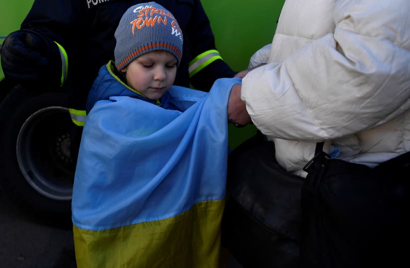  Ivan Iustushenko, 5, is wrapped in a Ukrainian flag by his grandmother after fleeing from Mariupol in Ukraine to Romania, following Russia's invasion of Ukraine, at the border crossing in Siret, Romania, March 22, 2022. (photo credit: REUTERS/CLODAGH KILCOYNE)