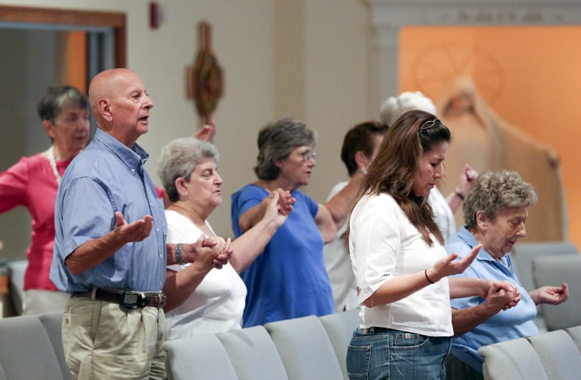  Parishioners join hands as they pray the "Our Father" prayer during a mass in 2015. (photo credit: REUTERS/CHRIS KEANE)