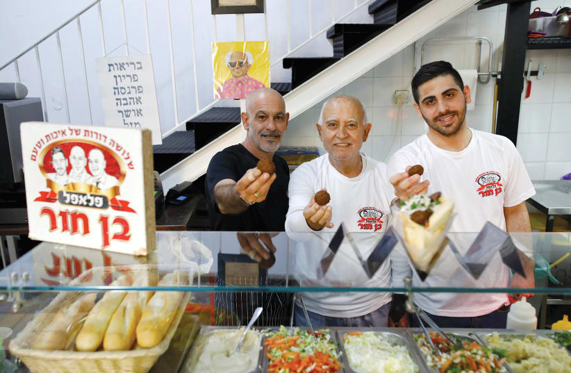  Tomer, Aharon and Oz Ben Hur offer freshly fried falafel balls at the Ben Hur Falafel restaurant in Tel Aviv. (photo credit: AMIR COHEN/REUTERS)