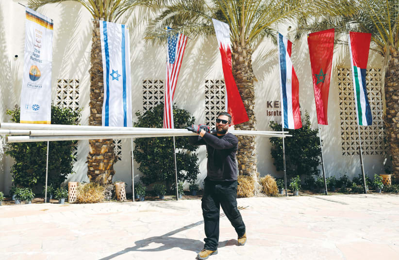  A WORKER carries flagpoles in preparation for the Negev Summit in Sde Boker on March 27. (photo credit: AMIR COHEN/REUTERS)
