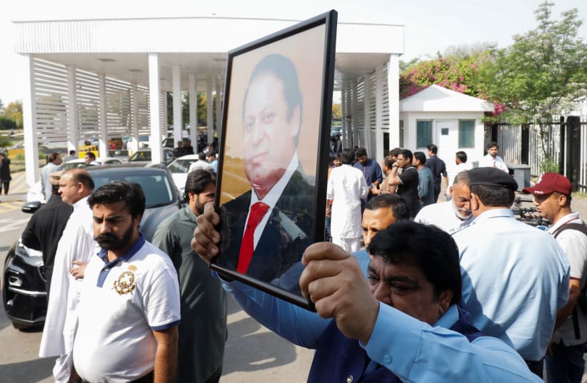  A Pakistani lawmaker holds a photo of former prime minister Nawaz Sharif as he walks towards the parliament house building to cast his vote on a motion of no-confidence to oust Prime Minister Imran Khan, in Islamabad, Pakistan April 3, 2022.  (photo credit: REUTERS/AKHTAR SOOMRO)