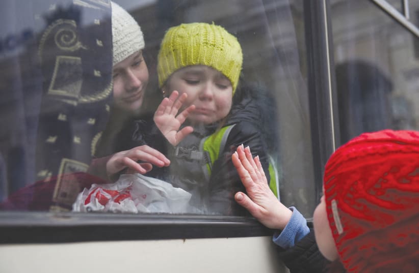  ALEXANDRA, 12, holds her sister Esyea, 6, who cries as she waves at her mother, Irina, while members of the Odesa Jewish community board a bus last month to flee Russia’s invasion of Ukraine. (photo credit: ALEXANDROS AVRAMIDIS/REUTERS)