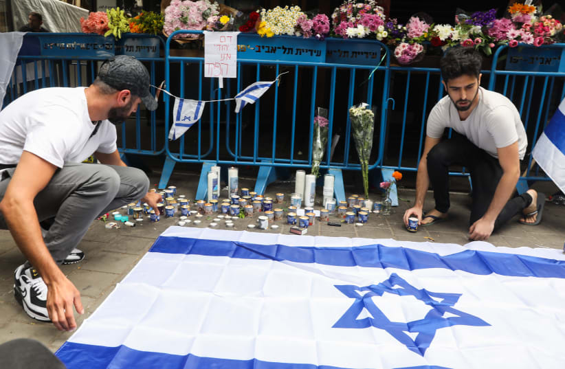  Israelis light candles at the scene of a terror attack on Dizengoff street, central Tel Aviv. 2 people were killed and several more injured in last night terror attack, April 8, 2022.  (photo credit: NOAM REVKIN FENTON/FLASH90)