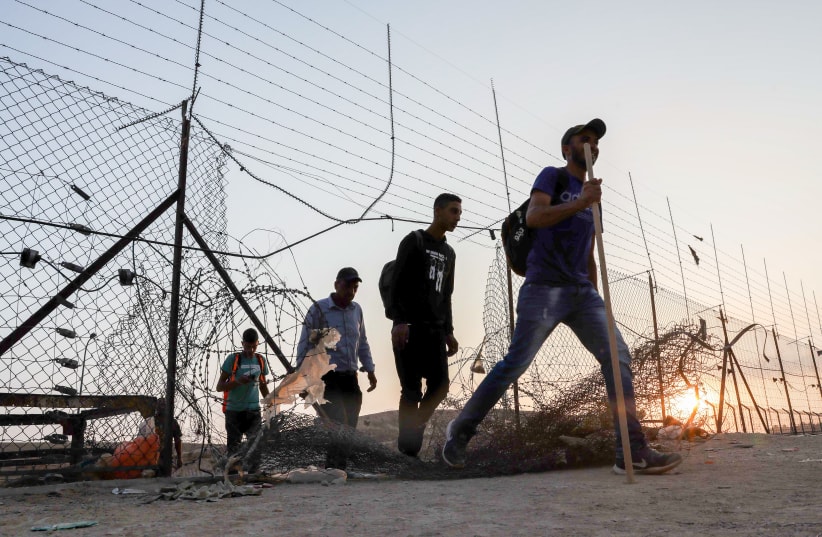  Palestinian workers cross to Israel through a hole in the security fence near the West Bank city of Hebron, July 25, 2021.  (photo credit: WISAM HASHLAMOUN/FLASH90)