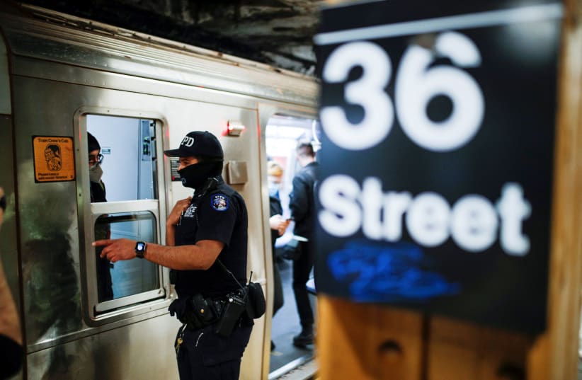 A New York Police Officer of the anti terrorism unit speaks with a MTA worker as he patrols the 36th St. subway station, a day after a shooting incident took place in the Brooklyn borough of New York City, US, April 13, 2022. (photo credit: REUTERS/EDUARDO MUNOZ)