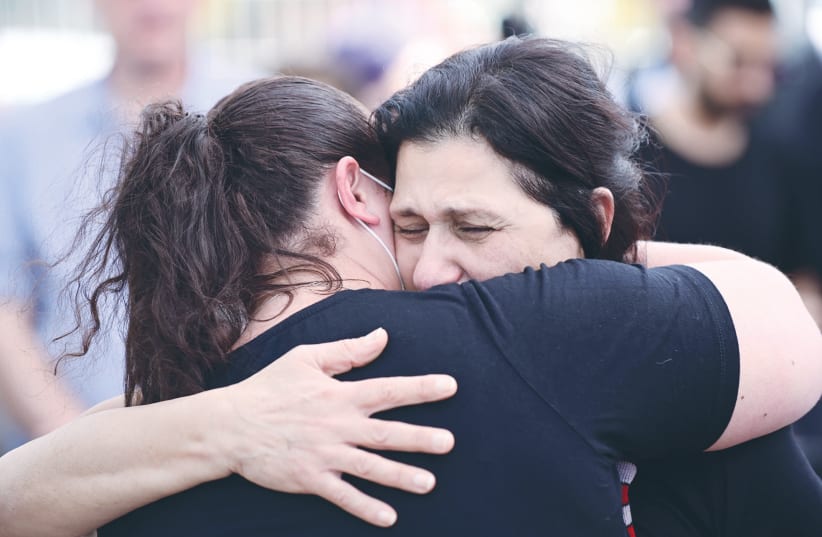  MOURNERS EMBRACE at the funeral of Tomer Morad at the Kfar Saba cemetery on Sunday, after he was murdered in last week’s terrorist attack in Tel Aviv.  (photo credit: TOMER NEUBERG/FLASH90)