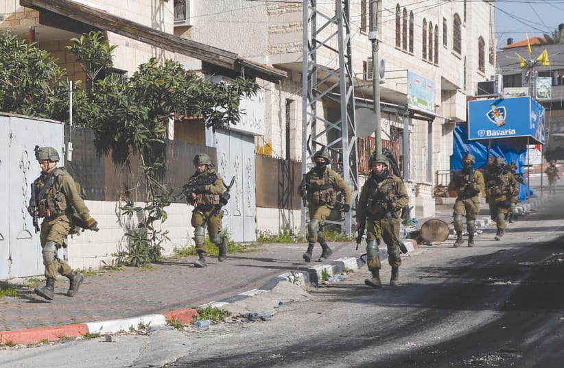  IDF SOLDIERS RUN down a street in Jenin during a raid last week. (photo credit: MOHAMAD TOROKMAN/REUTERS)