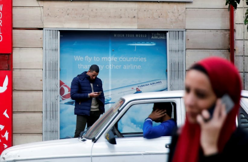  People use their mobile phones in front of the office of Turkish airlines in Cairo, Egypt December 24, 2017.  (photo credit: REUTERS/AMR ABDALLAH DALSH)