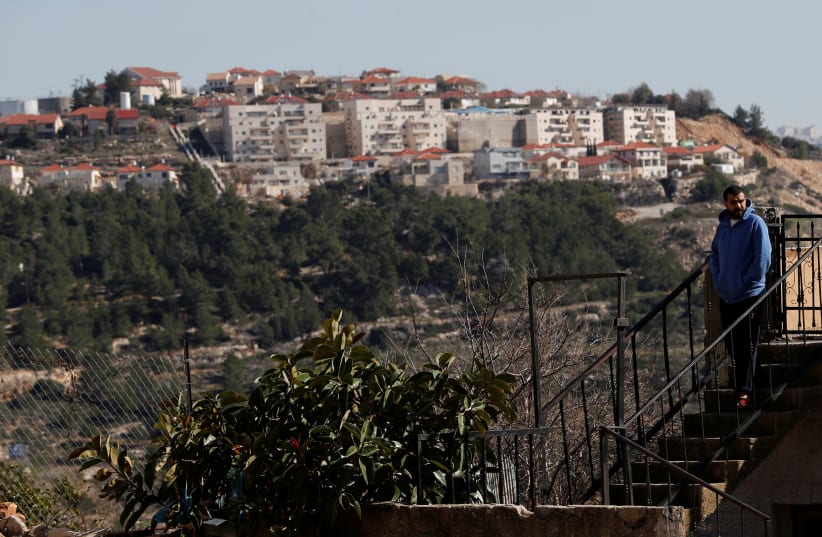  A Palestinian man walks down the stairs of a building as the Israeli settlement of Dolev is seen, near Ramallah in the West Bank January 26, 2020. Picture taken January 26, 2020. (photo credit: REUTERS/MOHAMAD TOROKMAN)