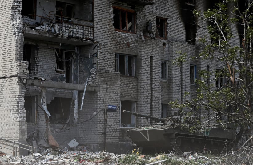  A Russian infantry fighting vehicle is seen in front of an apartment building heavily damaged during Ukraine-Russia conflict in the town of Popasna in the Luhansk Region, Ukraine May 26, 2022 (photo credit: REUTERS/ALEXANDER ERMOCHENKO)
