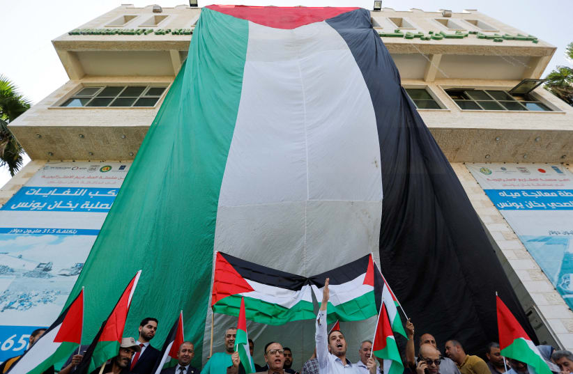  Palestinians wave Palestinian flags during a protest over tensions in Jerusalem's al-Aqsa Mosque on Jerusalem Day, in Khan Younis, in the southern Gaza Strip May 29, 2022.  (photo credit: IBRAHEEM ABU MUSTAFA/REUTERS)