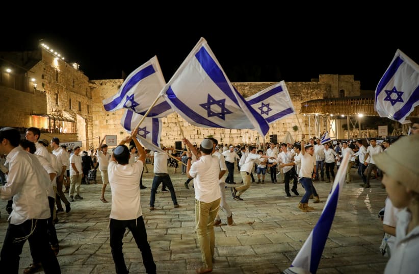  Men dance with Israeli flags at the Western Wall in Jerusalem Old City on the eve of Jerusalem Day, Saturday night. (photo credit: NOAM REVKIN FENTON/FLASH90)