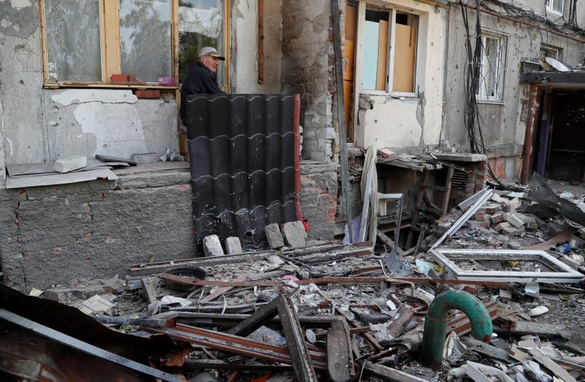  Pensioner Gennady Ivanov, 83, sits outside a residential building heavily damaged during Ukraine-Russia conflict in the southern port city of Mariupol, Ukraine May 30, 2022.  (photo credit: REUTERS/ALEXANDER ERMOCHENKO)