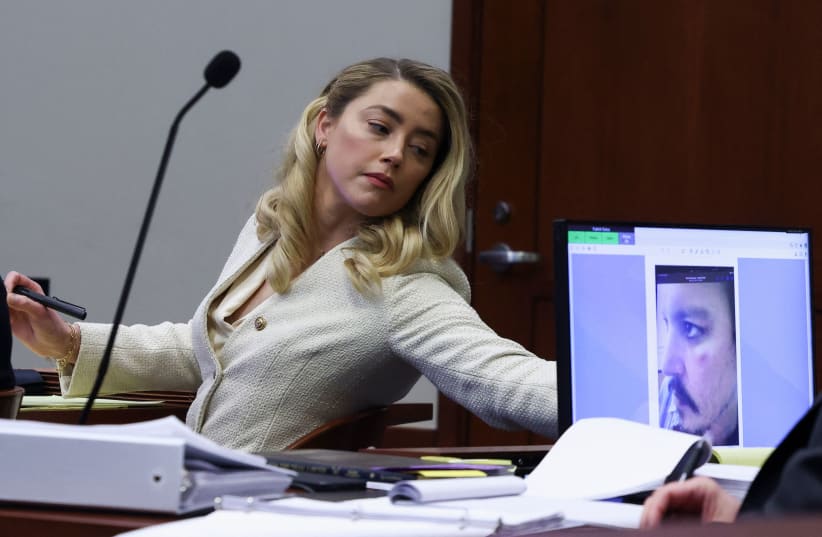  ACTRESS AMBER HEARD listens to ex-husband Johnny Depp as a picture of an injury to his face is seen on screen, during his defamation trial against her, April 20.  (photo credit: Evelyn Hockstein/Pool/AFP via Getty Images)