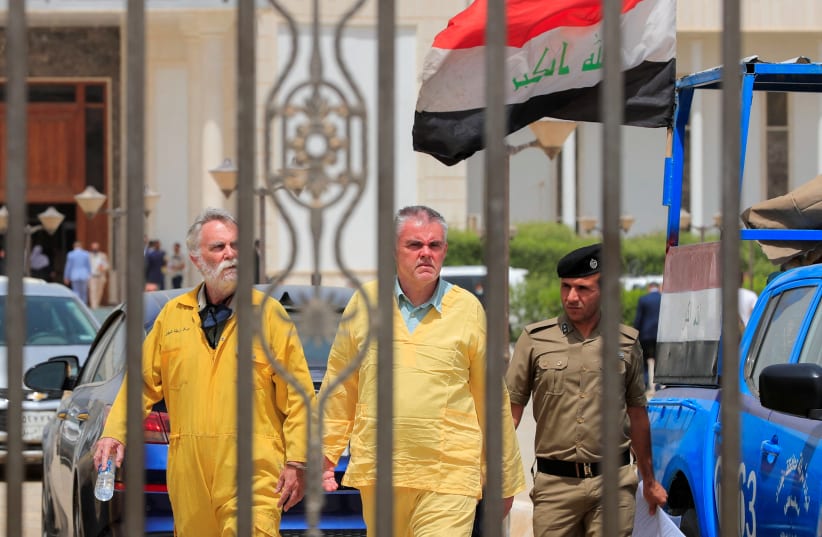  Iraqi policemen escort Jim Fitton from Britain and Volker Waldmann from Germany in handcuffs, who are suspected of smuggling ancient artefacts out of Iraq, outside a court in Baghdad, Iraq, May 22, 2022. (photo credit: REUTERS/THAIER AL-SUDANI)
