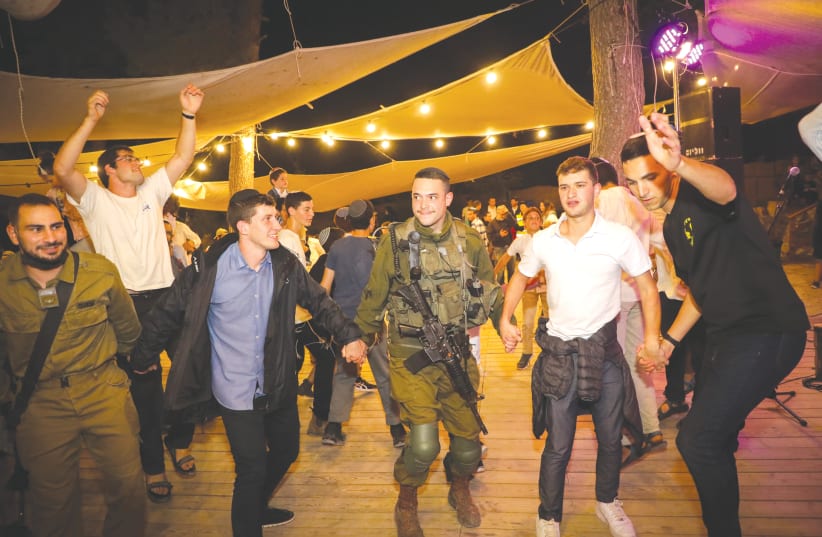 SOLDIERS AND civilians dance at a Simhat Torah celebration in September. Israeli Judaism is rooted in authentic Jewish tradition, infused with passion, spirituality and relevance, says the writer. (photo credit: GERSHON ELINSON/FLASH90)