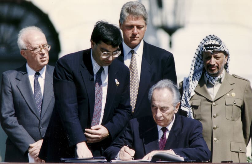  THEN-FOREIGN MINISTER Shimon Peres signs the Oslo Accords, witnessed by (from R) PLO chairman Yasser Arafat, prime minister Yitzhak Rabin and US president Bill Clinton, at the White House, Sept. 13, 1993. (photo credit: GARY HERSHORN/REUTERS)