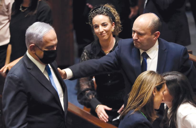  Bennett reaches out to Netanyahu as MK Idit Silman looks on following a vote on the new coalition in the Knesset on June 13, 2021. (photo credit: RONEN ZVULUN/REUTERS)