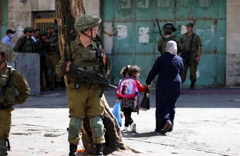  Israeli security forces guard as Jews (unseen) tour in the West Bank city of Hebron, during the Jewish holiday of Sukkot, September 22, 2021 (photo credit: WISAM HASHLAMOUN/FLASH90)